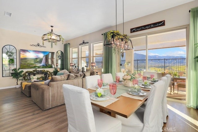 dining area featuring a mountain view, wood-type flooring, a chandelier, and a healthy amount of sunlight