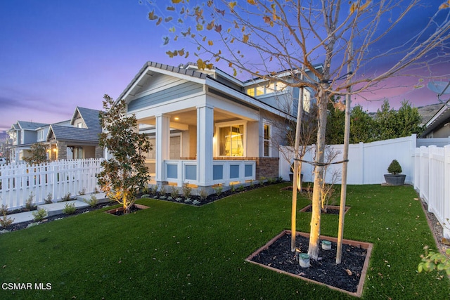 back house at dusk featuring a yard