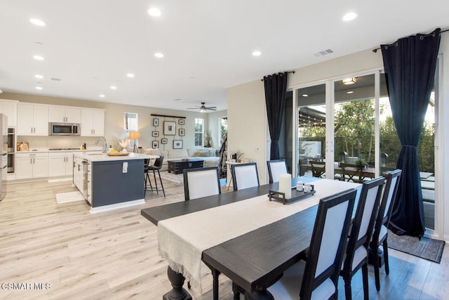 dining room with ceiling fan, sink, and light hardwood / wood-style flooring