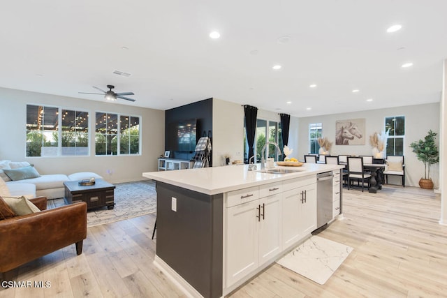 kitchen featuring white cabinets, light hardwood / wood-style flooring, sink, and an island with sink