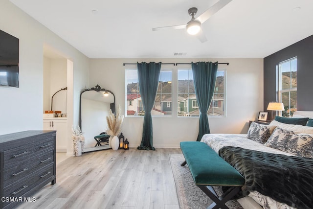 bedroom featuring light hardwood / wood-style floors, ceiling fan, and connected bathroom