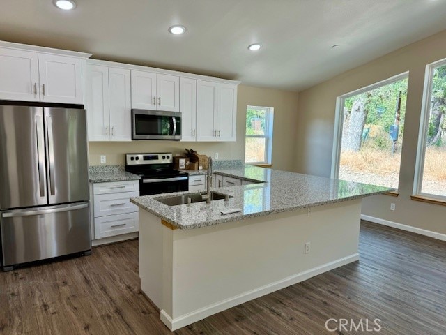 kitchen with appliances with stainless steel finishes, white cabinetry, light stone counters, dark hardwood / wood-style floors, and sink