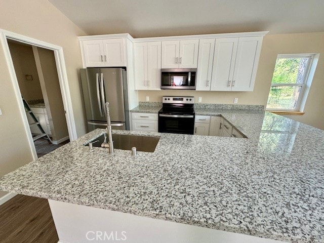 kitchen featuring white cabinets, vaulted ceiling, appliances with stainless steel finishes, and dark hardwood / wood-style flooring