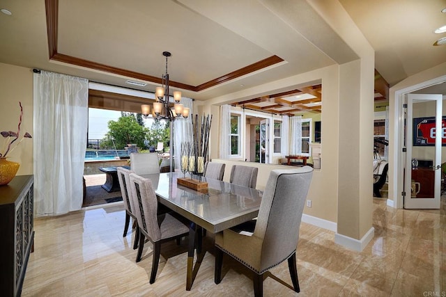 dining room featuring a notable chandelier, a raised ceiling, and crown molding