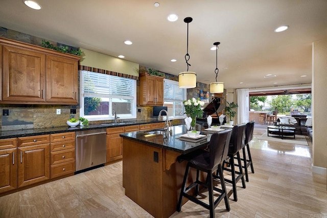 kitchen with hanging light fixtures, a kitchen island with sink, plenty of natural light, and stainless steel dishwasher