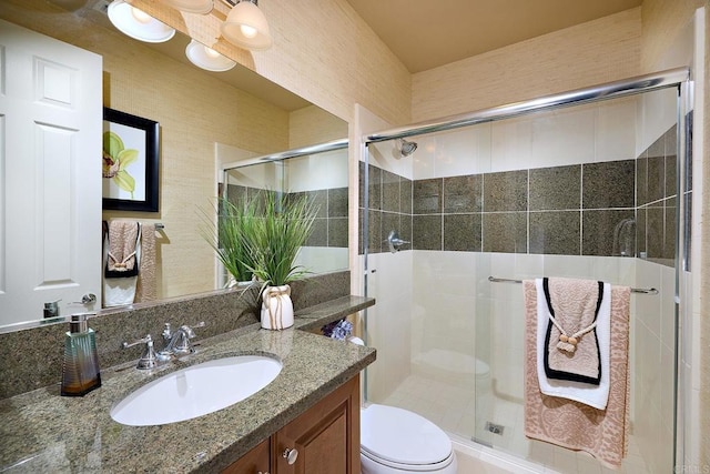 bathroom featuring a shower with door, vanity, and toilet