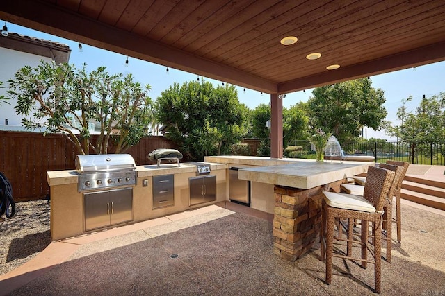 view of patio featuring an outdoor kitchen, an outdoor bar, and a grill