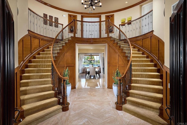 foyer featuring crown molding, a towering ceiling, and a chandelier