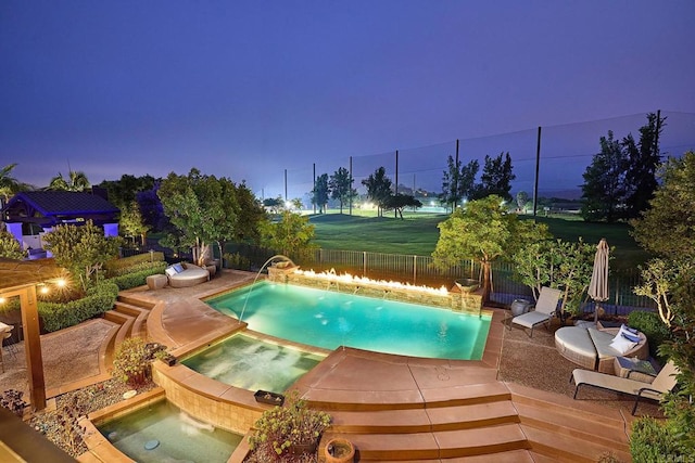 pool at dusk featuring an in ground hot tub, pool water feature, and a patio area