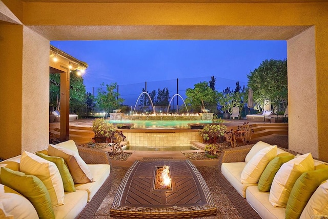 patio terrace at dusk featuring a fire pit, a pool, and pool water feature