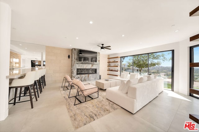 living room with a large fireplace, light tile patterned floors, and ceiling fan