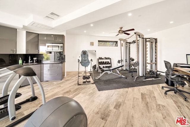 workout room with light hardwood / wood-style flooring and ceiling fan