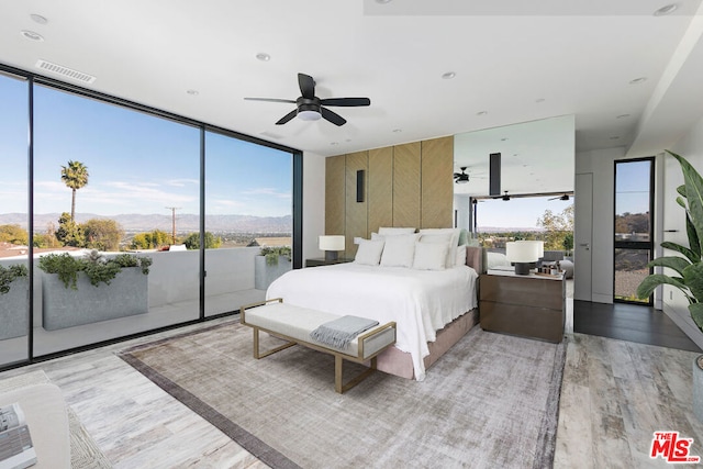 bedroom with ceiling fan, multiple windows, hardwood / wood-style flooring, and floor to ceiling windows