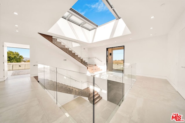 hallway with a skylight and light tile patterned flooring