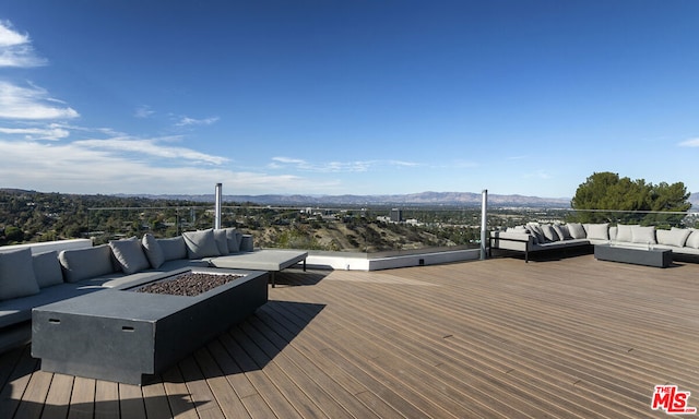 wooden deck featuring a mountain view and an outdoor living space with a fire pit