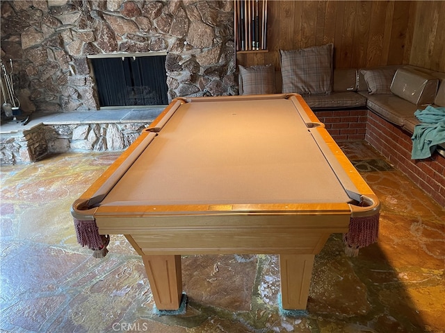 rec room with wood walls, pool table, and a fireplace