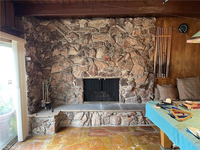 interior details featuring a stone fireplace, wood ceiling, wood walls, and beamed ceiling