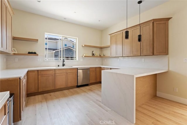 kitchen with sink, stainless steel dishwasher, light wood-type flooring, decorative light fixtures, and kitchen peninsula