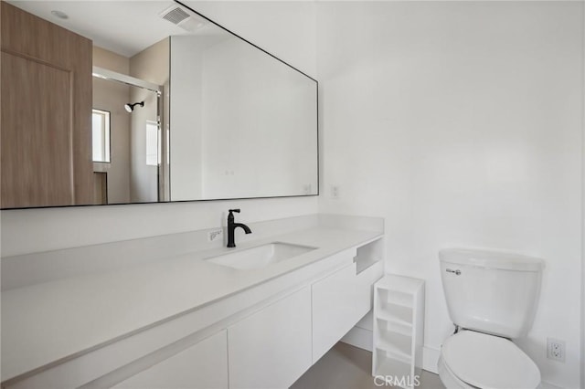 bathroom featuring vanity, toilet, and a shower with door