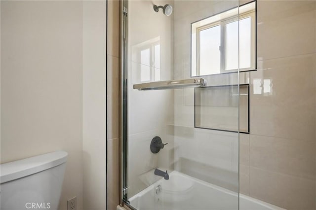 bathroom with toilet and combined bath / shower with glass door