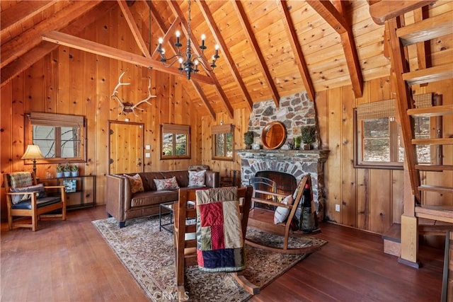 living room with wood ceiling, dark wood-type flooring, beamed ceiling, a fireplace, and an inviting chandelier