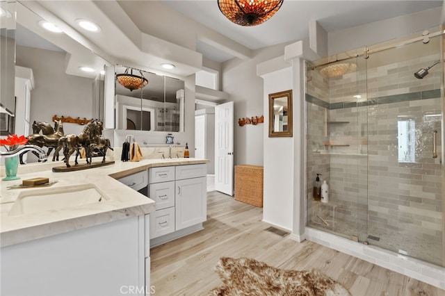 bathroom with a shower with door, vanity, and hardwood / wood-style floors