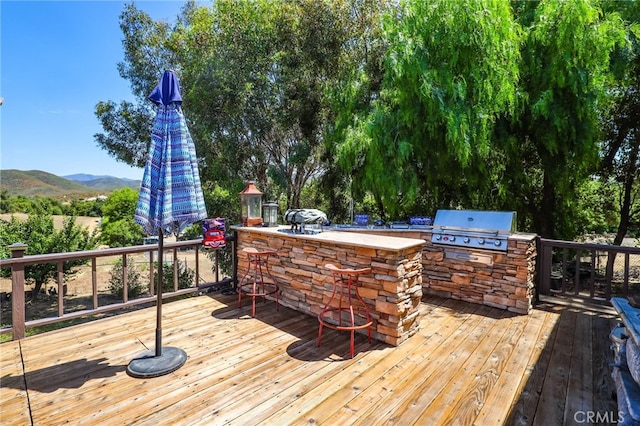 deck featuring a mountain view, a grill, and an outdoor kitchen