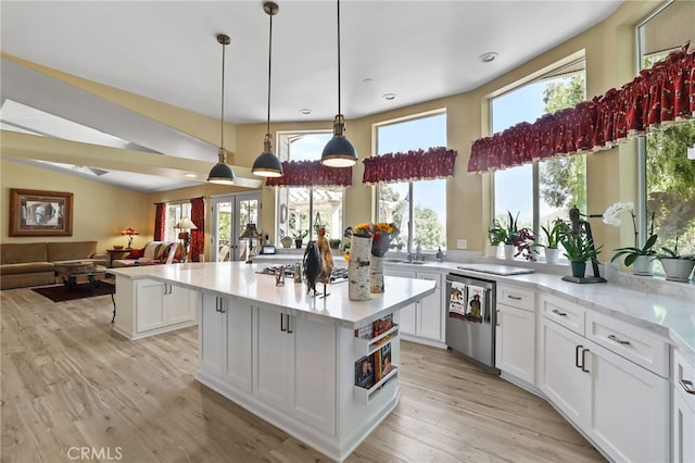 kitchen with sink, a center island, pendant lighting, white cabinetry, and light hardwood / wood-style floors