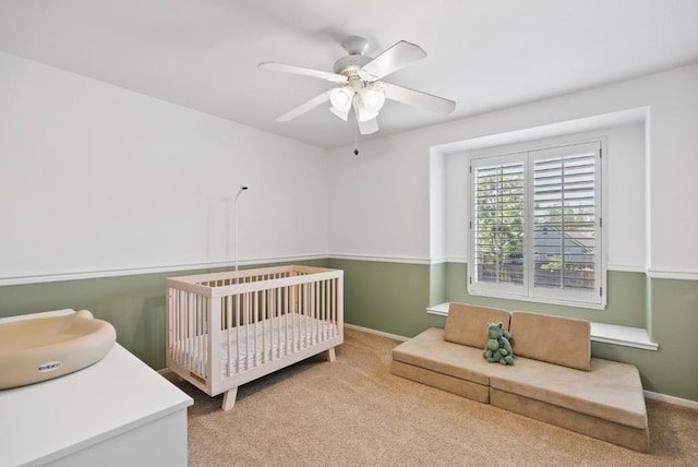 bedroom featuring light colored carpet, a crib, sink, and ceiling fan