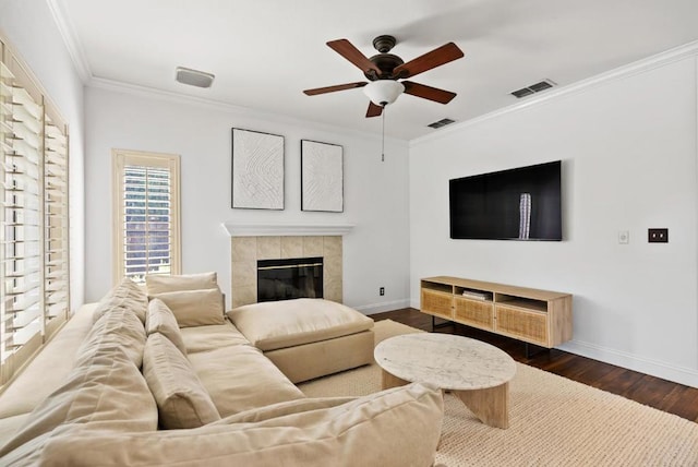 living room with ornamental molding, dark wood-type flooring, a fireplace, and ceiling fan