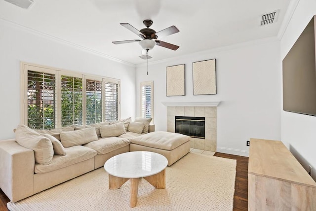 living room featuring ornamental molding, dark wood-type flooring, a fireplace, and ceiling fan