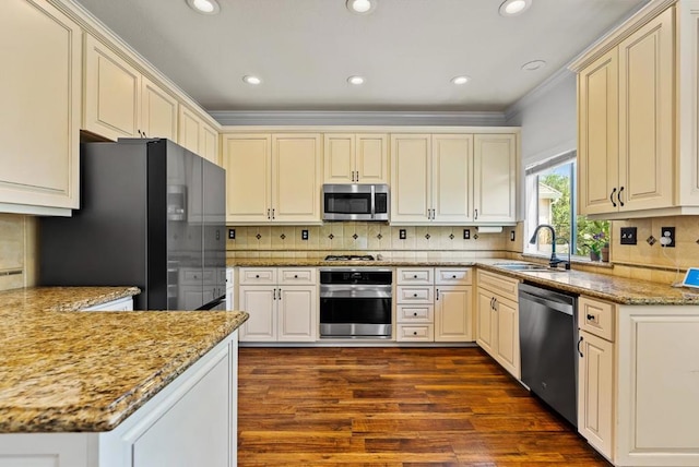 kitchen with cream cabinets, sink, dark hardwood / wood-style flooring, stainless steel appliances, and crown molding