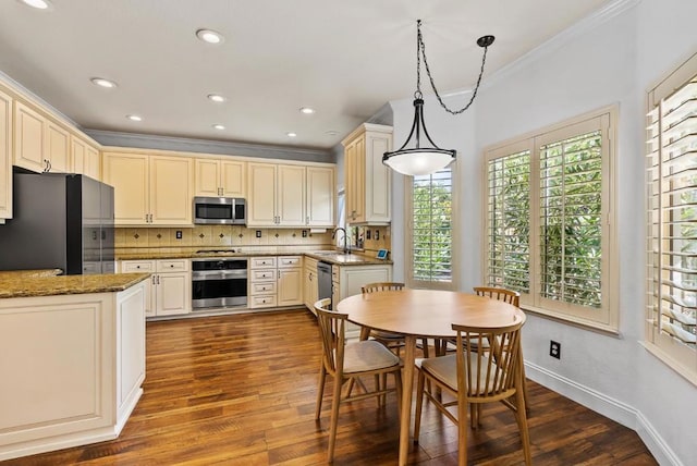 kitchen with hardwood / wood-style floors, stainless steel appliances, sink, crown molding, and decorative light fixtures