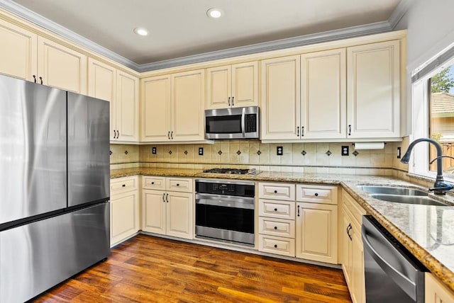 kitchen featuring appliances with stainless steel finishes, sink, cream cabinetry, hardwood / wood-style flooring, and ornamental molding