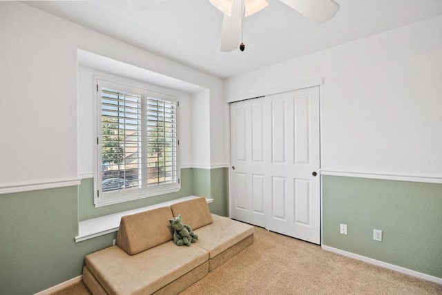 living area featuring light carpet and ceiling fan