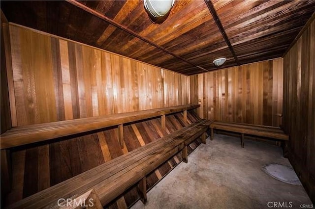 view of sauna / steam room with wooden ceiling, wood walls, and concrete floors