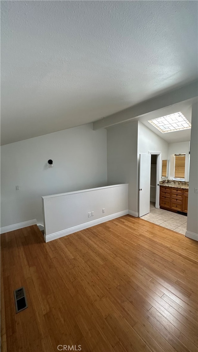 unfurnished living room with light hardwood / wood-style flooring and a textured ceiling