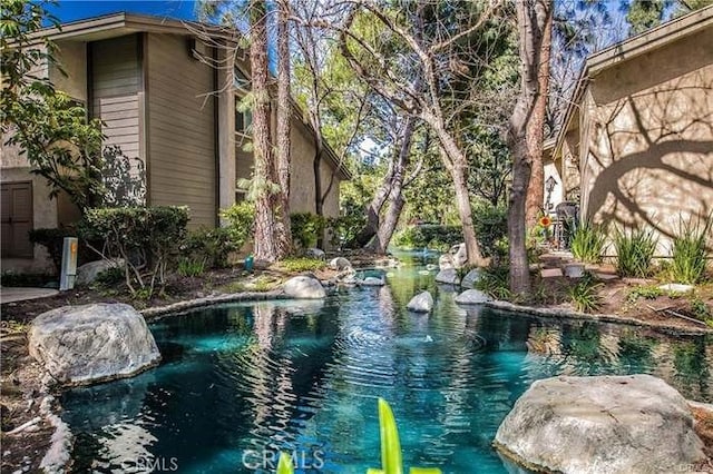 view of swimming pool with a small pond