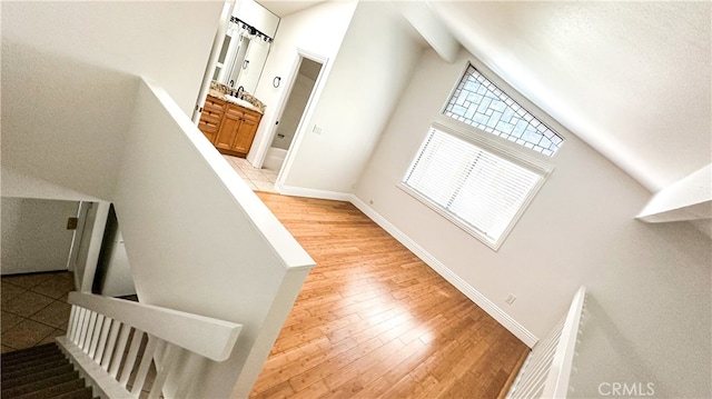 stairway featuring lofted ceiling with beams and hardwood / wood-style flooring