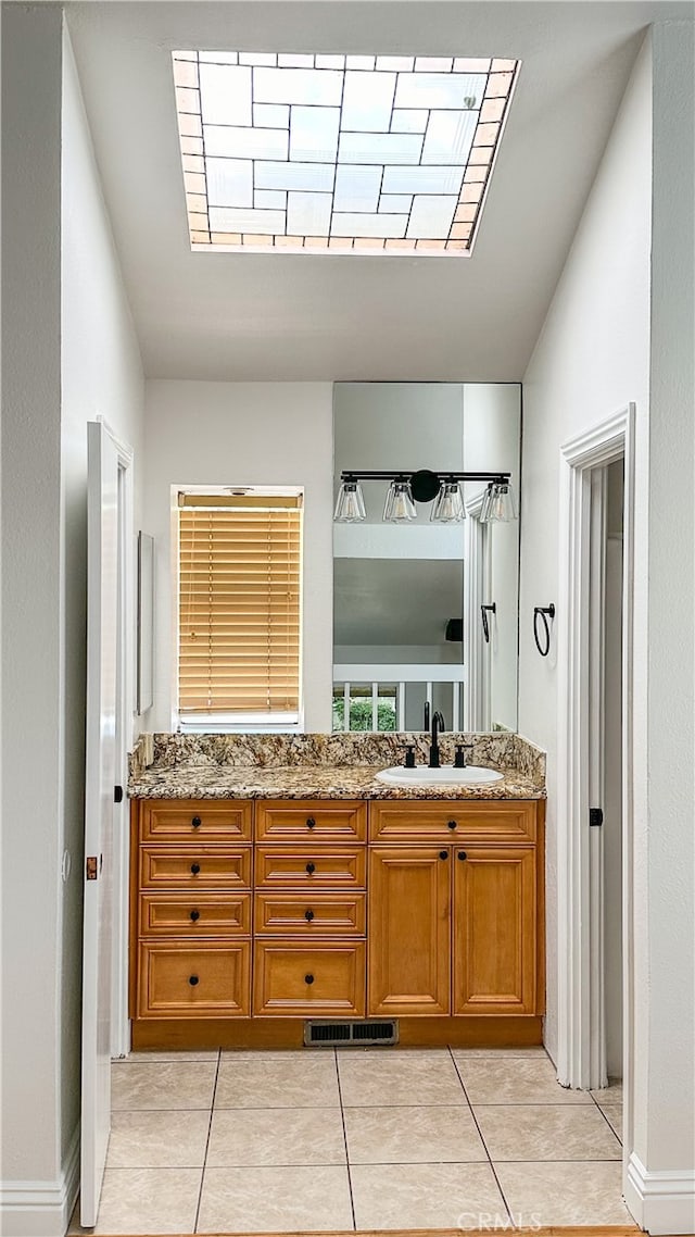 bathroom with vanity, vaulted ceiling, and tile patterned floors