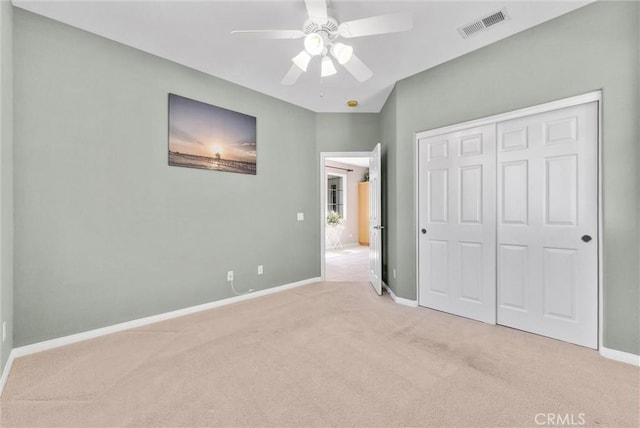 unfurnished bedroom with ceiling fan, a closet, and light carpet