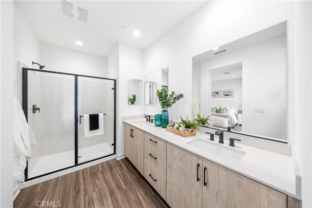 bathroom with wood-type flooring, vanity, and a shower with door