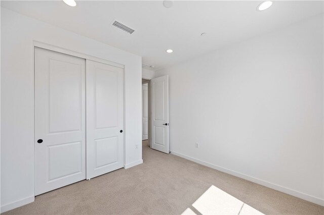 unfurnished bedroom featuring light colored carpet and a closet