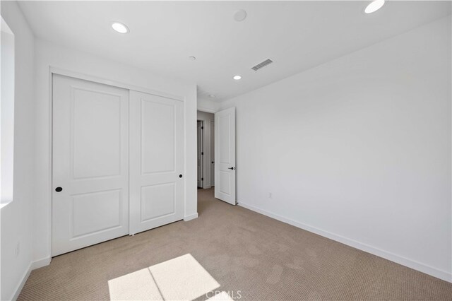 unfurnished bedroom with a closet and light colored carpet