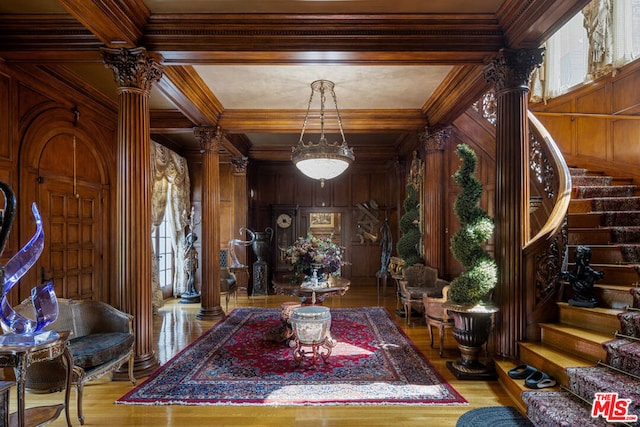 interior space with wood-type flooring, ornamental molding, beam ceiling, and decorative columns