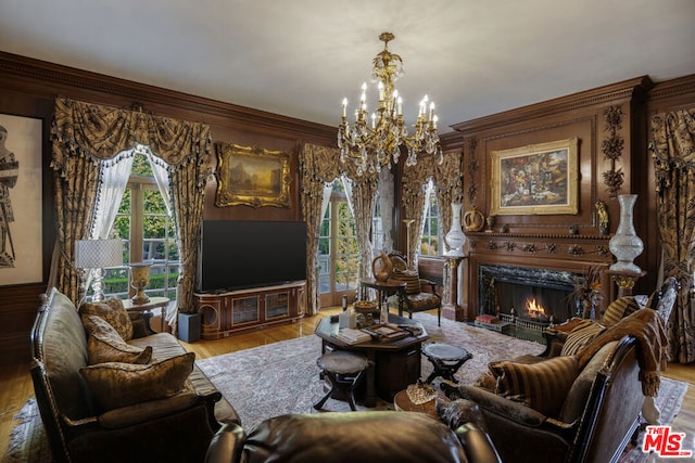 living room with ornamental molding, an inviting chandelier, a fireplace, and light hardwood / wood-style floors