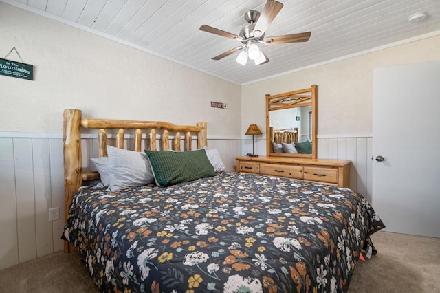 carpeted bedroom featuring ceiling fan, wood walls, ornamental molding, and wooden ceiling