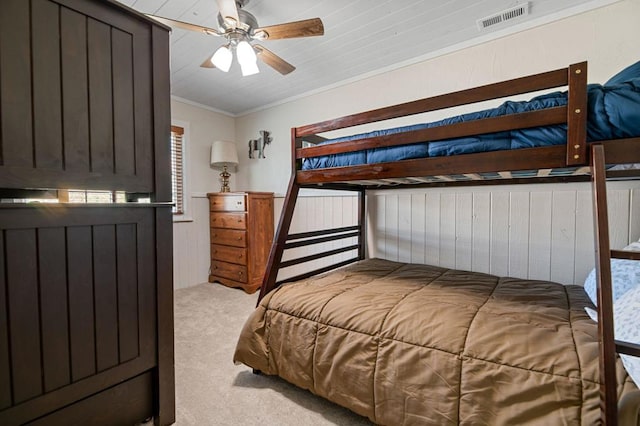 bedroom with ceiling fan, wood walls, ornamental molding, and light colored carpet