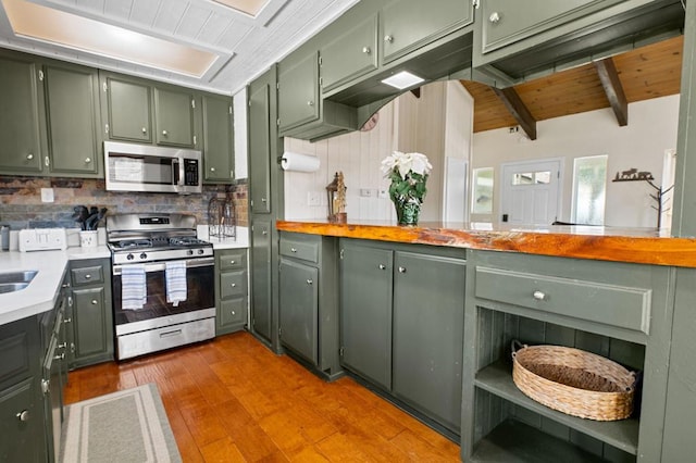 kitchen with beam ceiling, stainless steel appliances, wooden ceiling, green cabinetry, and light wood-type flooring