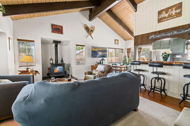 living room with wood-type flooring, a wood stove, wooden ceiling, beamed ceiling, and high vaulted ceiling